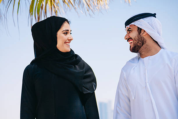 Young Emirati couple with traditional wear having fun on the beach